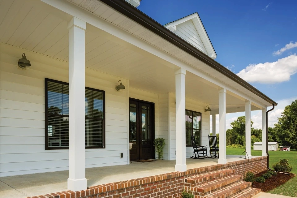 White lap siding with white trim on a home with a covered front porch and brick steps.